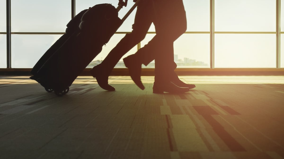Flugbegleiter Symbolbild: Silhouette zweier Reisender, die ihren Koffer hinter sich herziehen