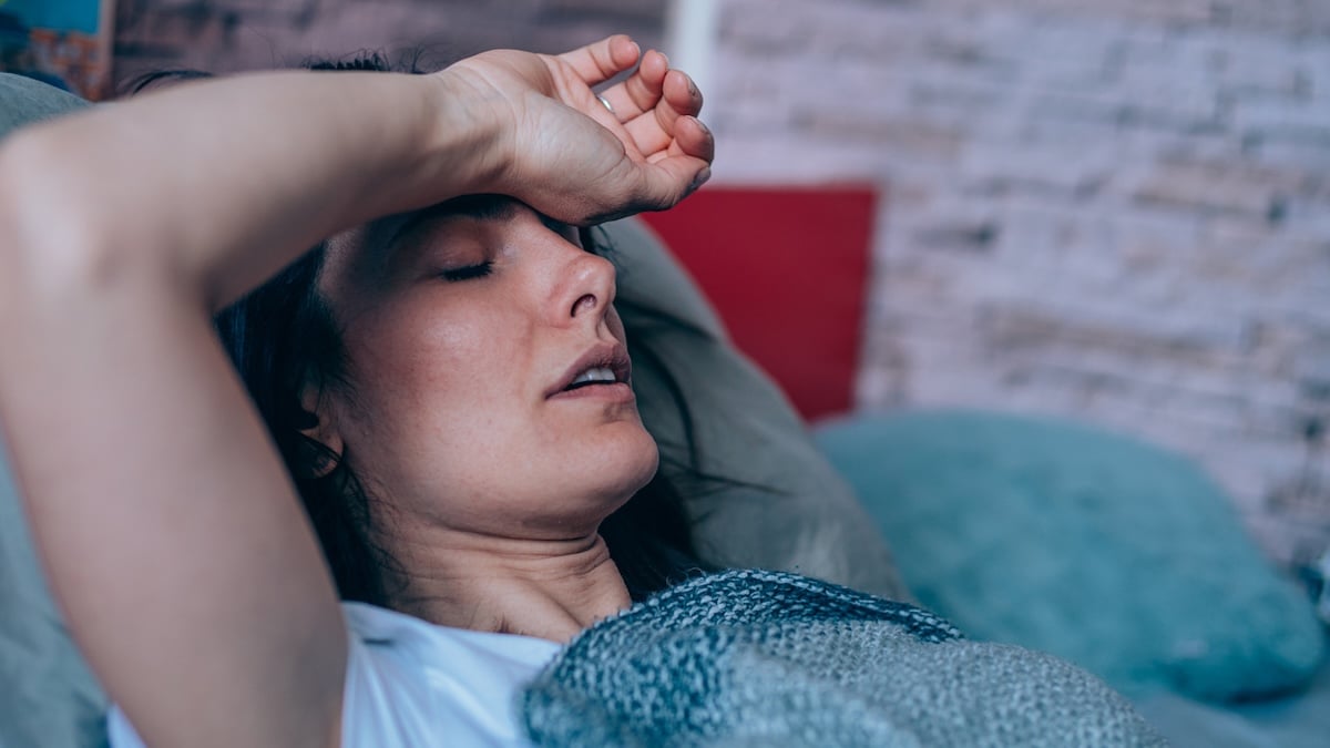 Freizeitkrankheit Symbolbild: Frau liegt krank im Bett