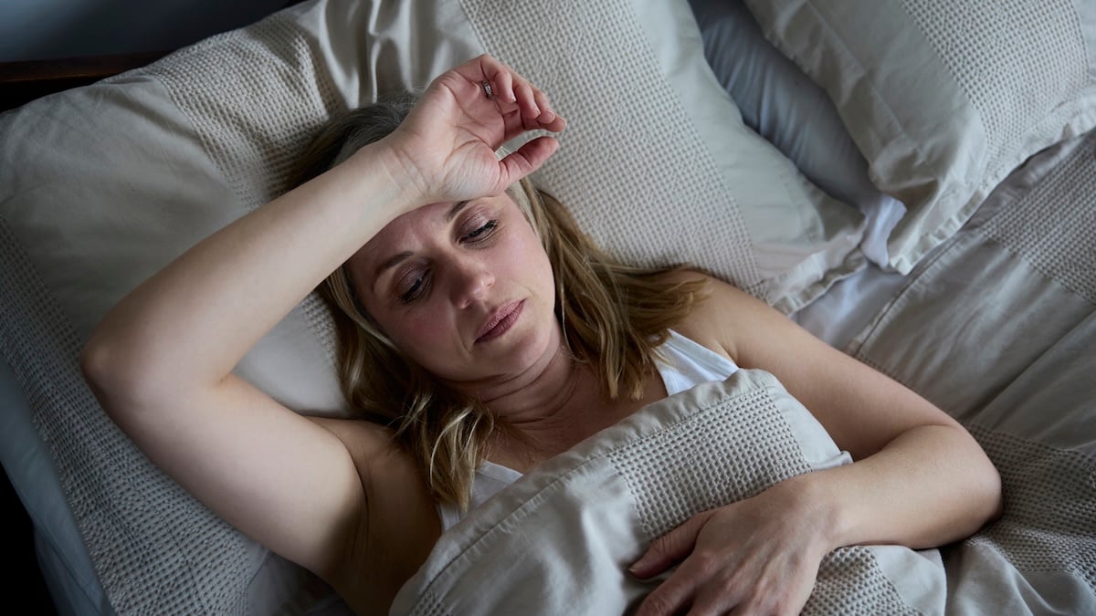 Nachtschweiß als Krebssymptom: Frau, die an Schlaflosigkeit im Bett zu Hause leidet