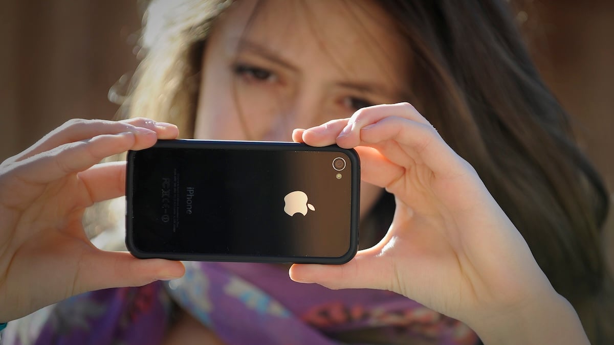 Nackterkennung iPhone Symbolbild: junge Frau hält ein iPhone horizontal in der Hand