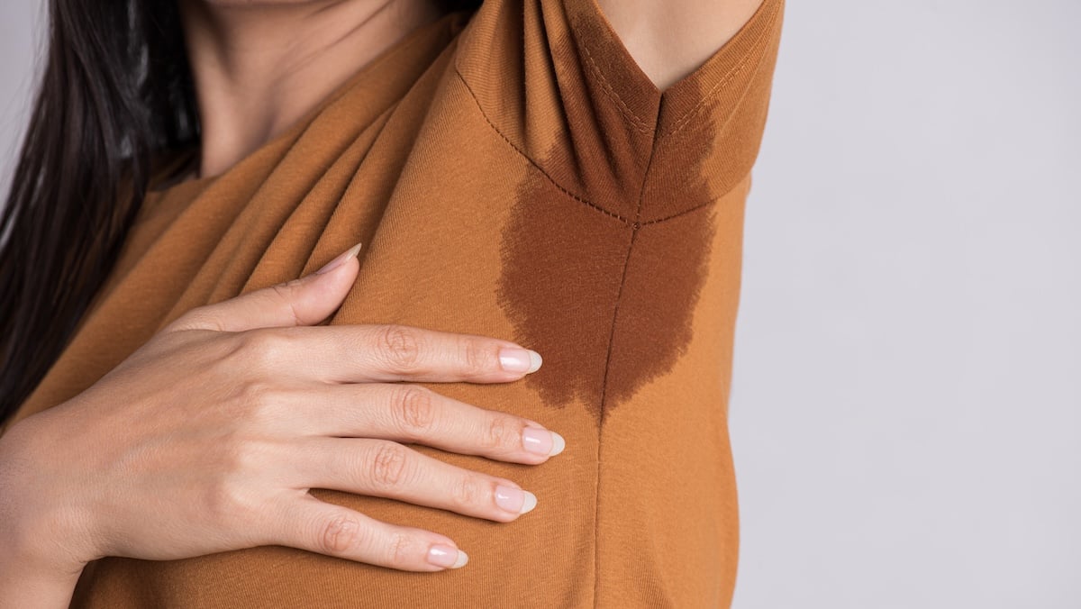 Schwitzen: Frau mit Schweißfleck unter dem Arm