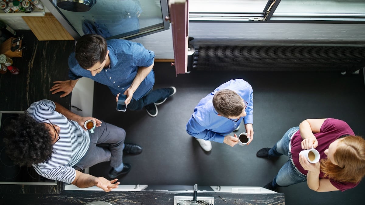Eine Gruppe Arbeitnehmer trifft sich für Kaffeepause in der Küche im Büro