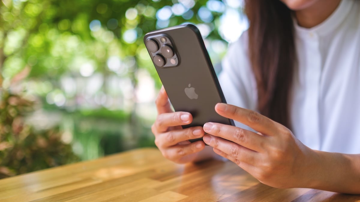 Kaum jemand kennt sie: Das iPhone hat eine geheime Taste 4 Junge Frau hält schwarzes iPhone so in der Hand, dass man dessen Rückseite gut sehen kann