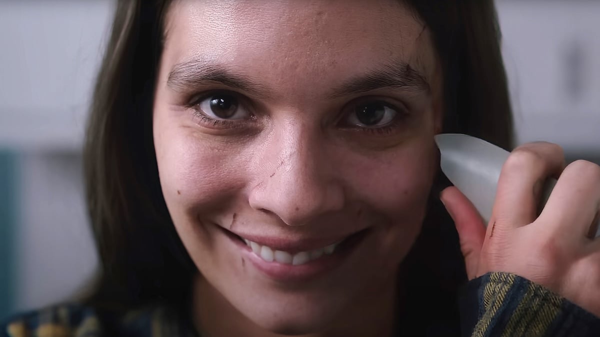 Laut Studie: Das sind die gruseligsten Horrorfilme aller Zeiten 1 Szene aus dem Horrorfilm „Smile“, in der eine braunhaarige junge Frau wirr in die Kamera lächelt