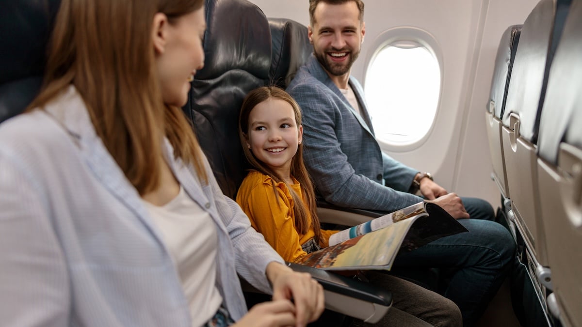 Kleidung im Flugzeug: Lächelnde Familie mit Kind sitzt an Bord eines Fliegers