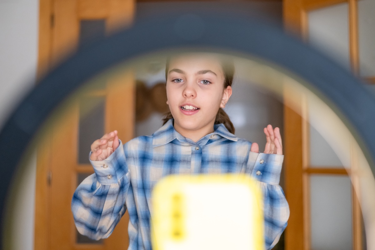 Kinder als „Sinnfluencer“: Junges Mädchen steht vor einer Handy-Kamera und einem Ringlicht, um ein Video aufzunehmen