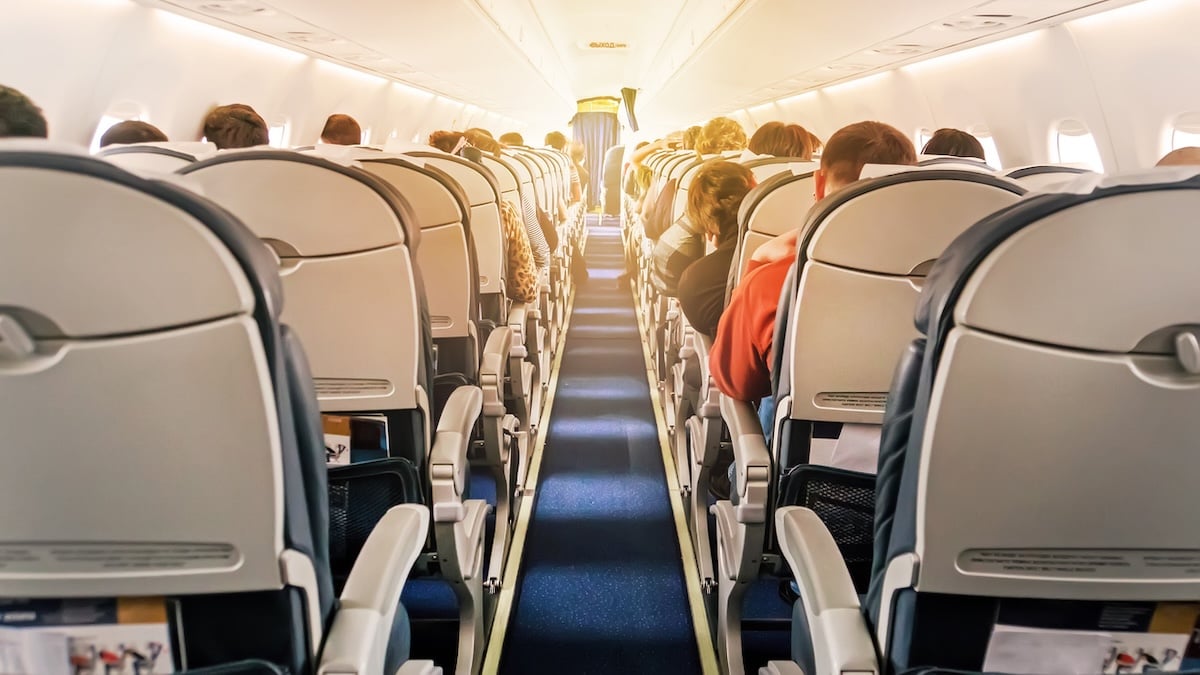 Welche Kleidung man laut Experten niemals im Flugzeug tragen sollte 4 Kleidung im Flugzeug: Bild zeigt den Mittelgang eines Fliegers von hinten, alle Plätze sind besetzt