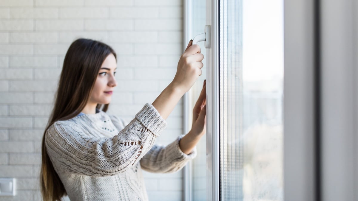 Junge Frau öffnet das Fenster zum Lüften