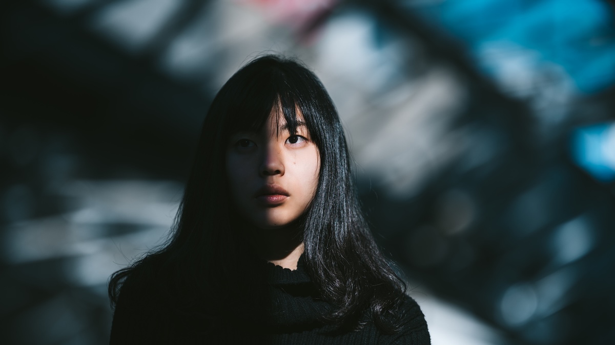 Narzissten erkennen Symbolbild: Ein Porträt einer jungen asiatischen Frau, während die Hälfte ihres ausdruckslosen Gesichts von der Sonne beleuchtet wird und die andere Hälfte im Schatten liegt