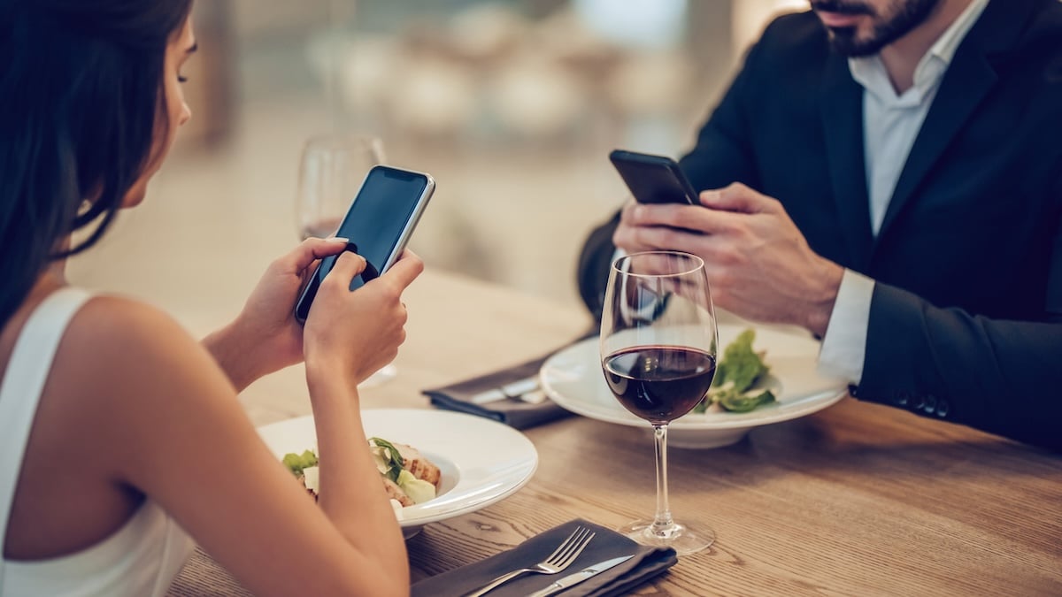 Gefährliche Angewohnheit: Wie das Smartphone Beziehungen zerstören kann 4 Paar sitzt im Restaurant, jeder ist mit seinem Smartphone beschäftigt