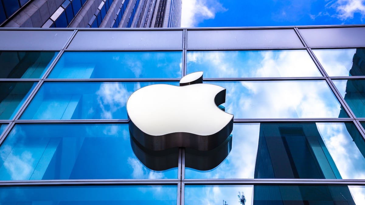 Apple-Logo an einer spiegelnden Glasfront in einer Großstadt