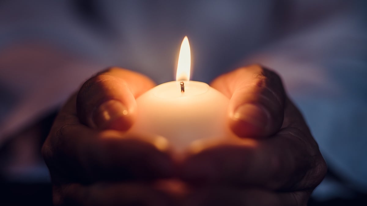 Symbolbild Kerzen: Frau hält kleine weiße Kerze in den Händen