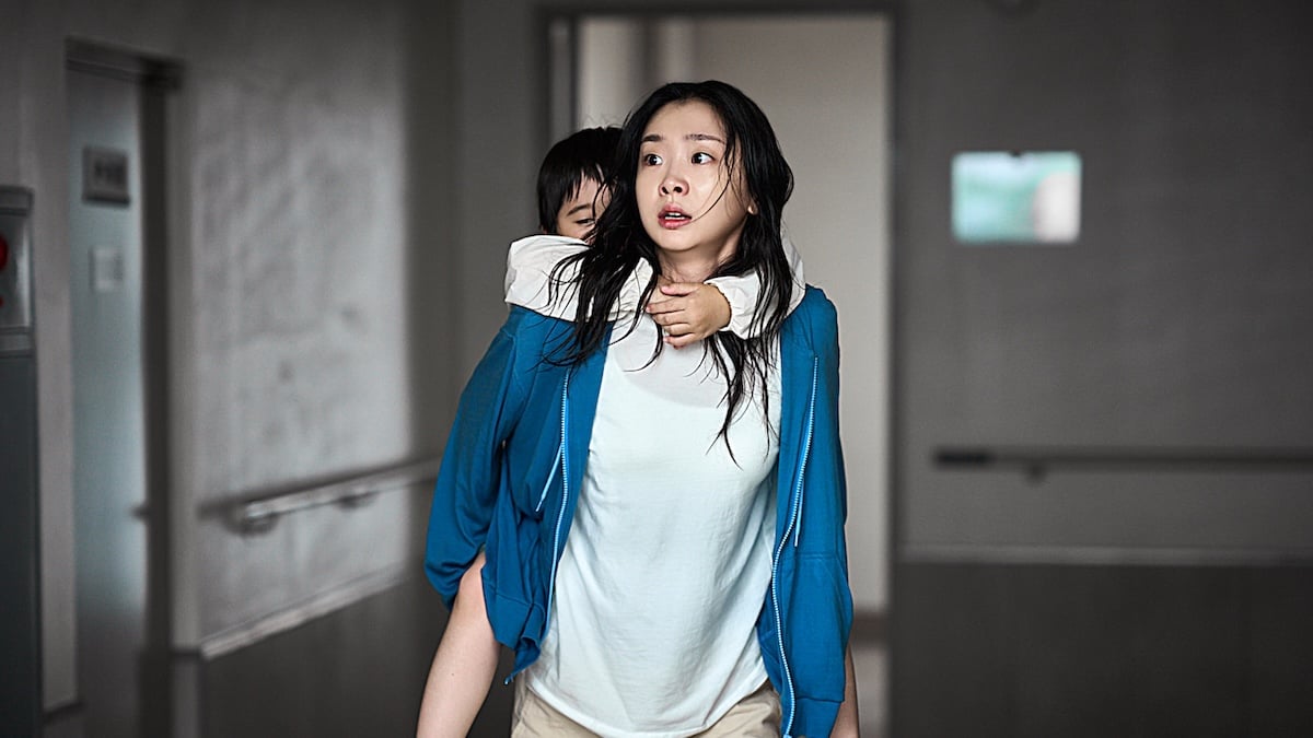 Szene aus dem Netflix-Film „The Great Flood“, in der eine Frau einen kleinen Jungen auf dem Rücken trägt