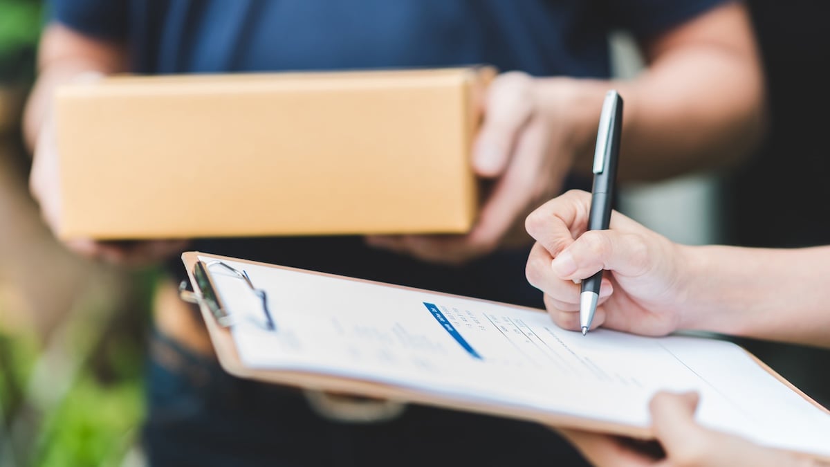 Polizei warnt: Deshalb sollte man keine Pakete für Nachbarn annehmen 9 Jemand nimmt Pakete von einem Zusteller entgegen und unterschreibt dafür einen Lieferschein
