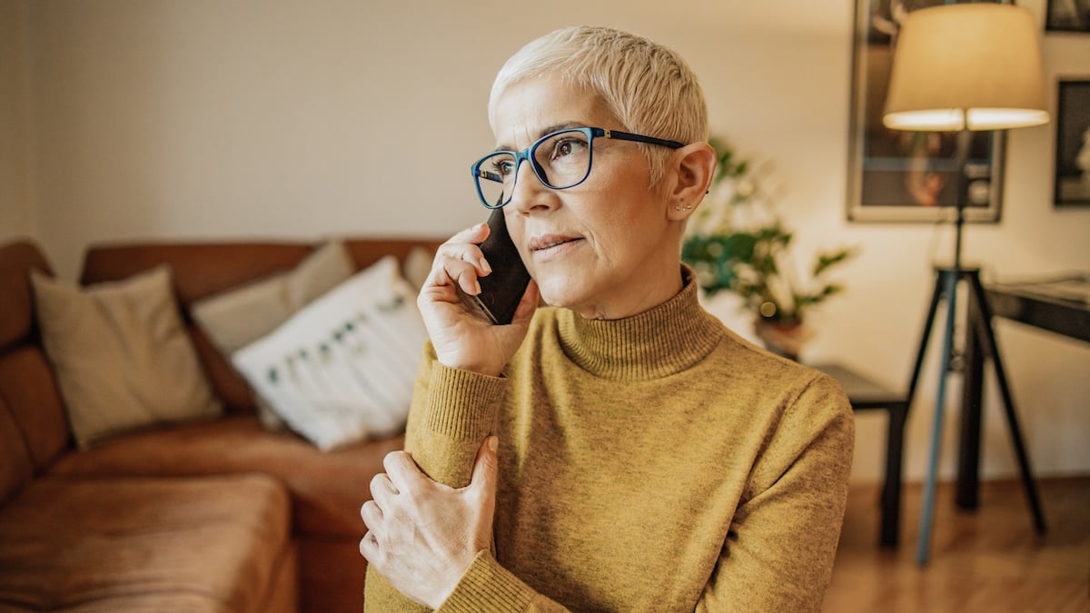Ältere Frau mit kurzen Haare und Brille am Telefon