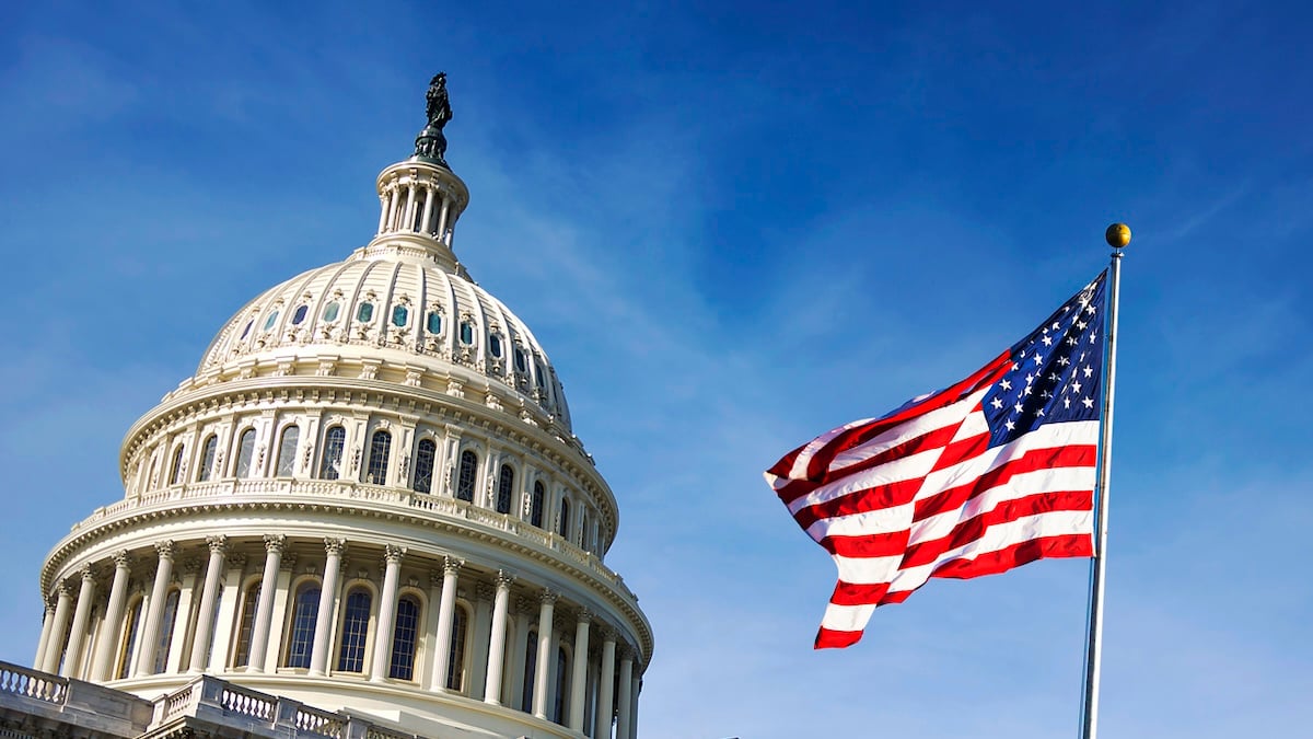 USA-Flagge vor blauem Himmel und dem Capitol Hill