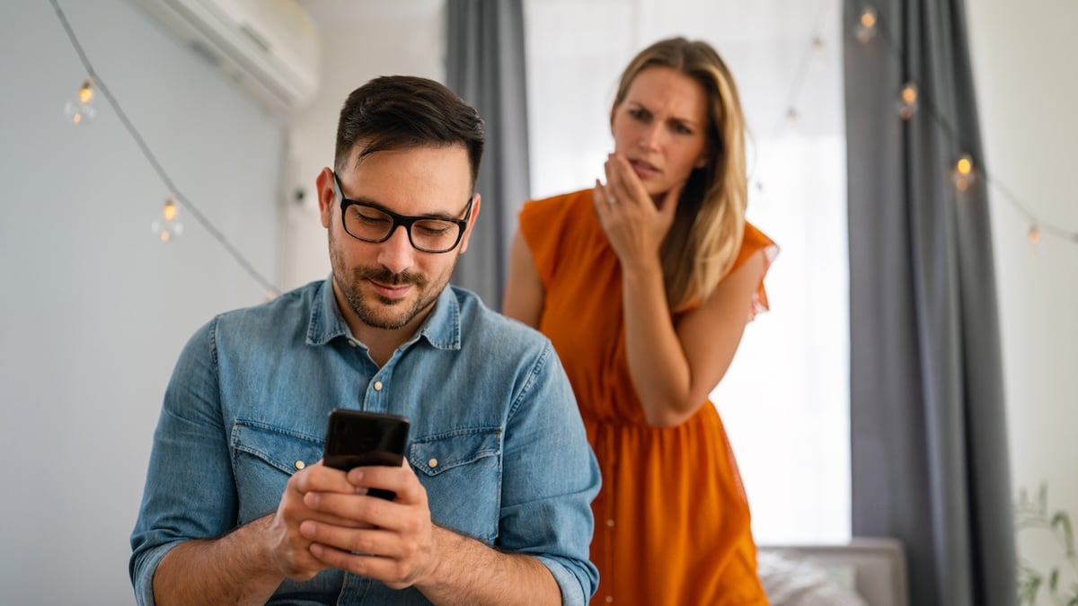 Nachrichten an Affäre: WhatsApp bietet Funktionen zum Fremdgehen 14 Affäre bei WhatsApp verstecken: Mann schaut lächelnd auf sein Handy, hinter ihm steht eine Frau