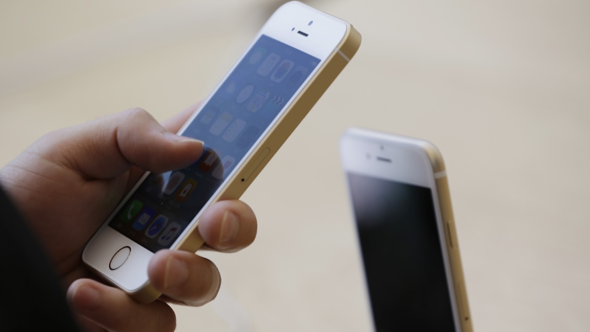 Jemand hält ein weißes iPhone SE (1. Generation) in der Hand